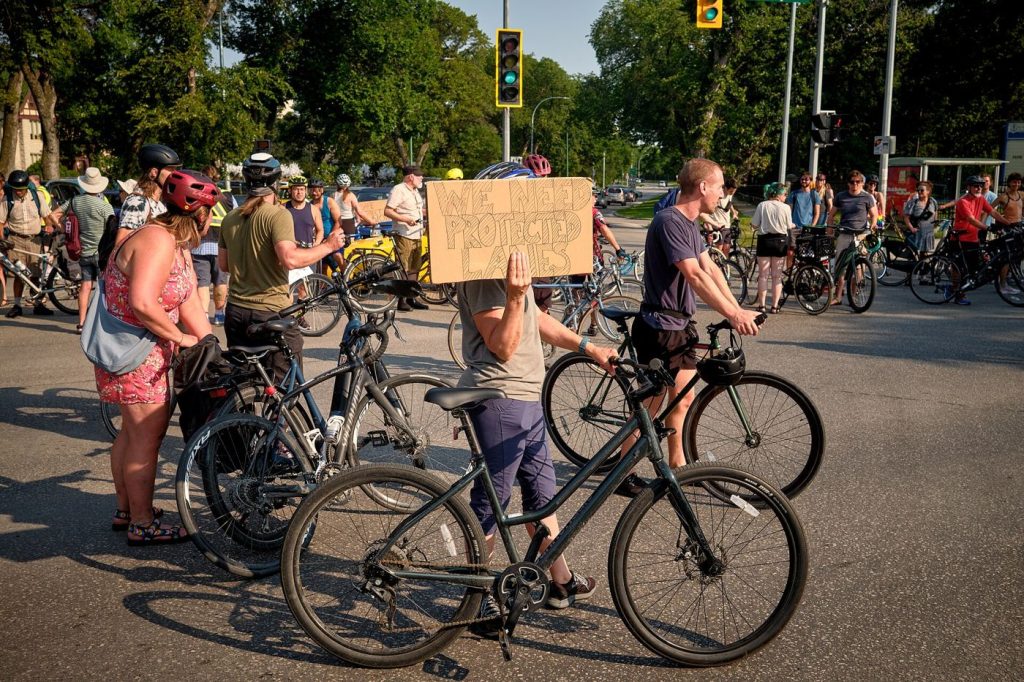 Cyclists ride safely along a protected bike lane separated from car traffic.