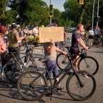 Cyclists ride safely along a protected bike lane separated from car traffic.